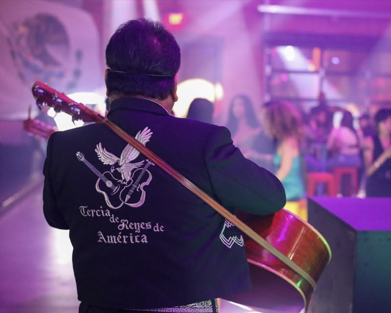 A mariachi band member playing a guitar