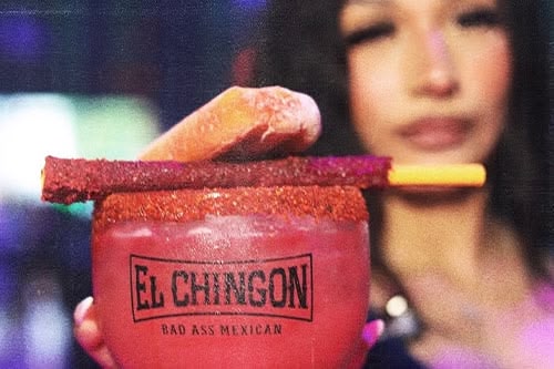 a photo of a waitress serving a signature El Chingon cocktail