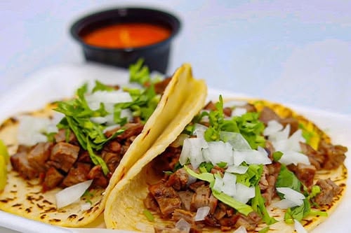 a photo of two street style tacos and salsa